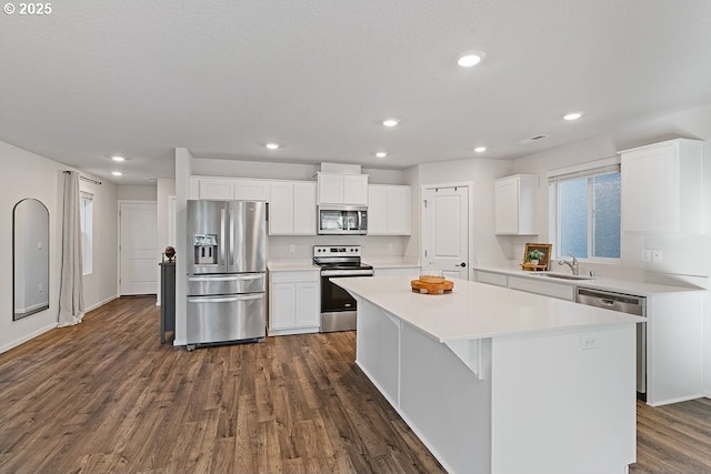 kitchen featuring a kitchen island, appliances with stainless steel finishes, white cabinetry, sink, and dark wood-type flooring