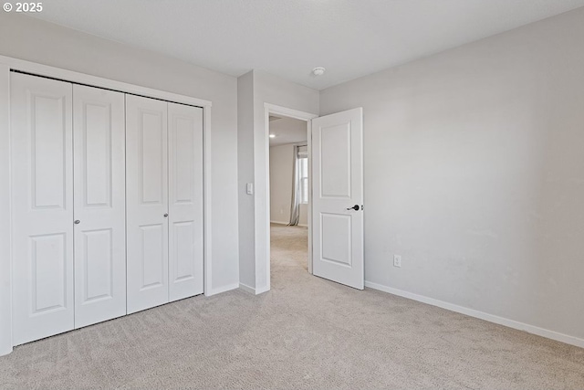 unfurnished bedroom with light colored carpet and a closet