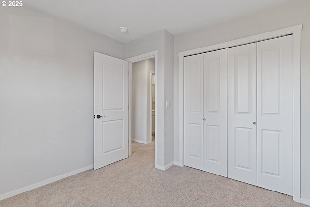 unfurnished bedroom featuring light colored carpet and a closet