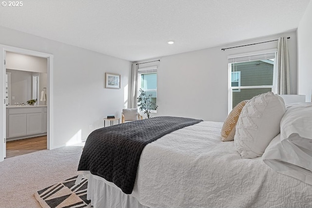 bedroom with light carpet, a textured ceiling, and ensuite bath