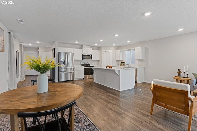 interior space with white cabinetry, dark hardwood / wood-style flooring, stainless steel appliances, and a center island