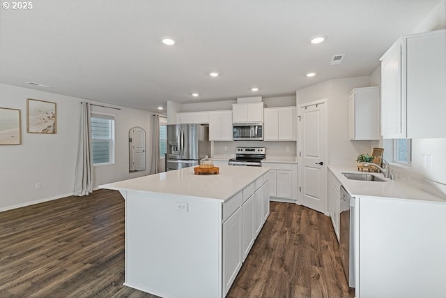 kitchen with a kitchen island, appliances with stainless steel finishes, dark hardwood / wood-style floors, sink, and white cabinets