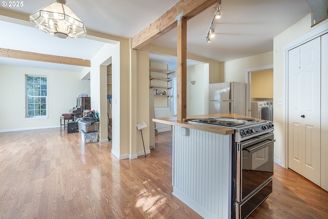 kitchen featuring black electric range, freestanding refrigerator, beam ceiling, light wood-type flooring, and washer and clothes dryer