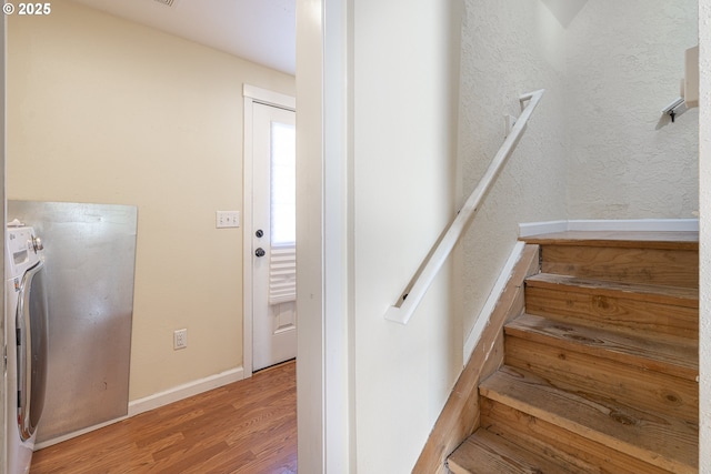 stairway with wood finished floors, washer / clothes dryer, and baseboards