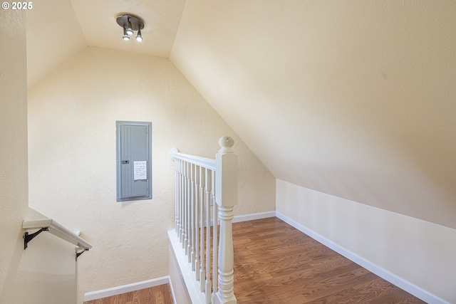 additional living space featuring electric panel, vaulted ceiling, wood finished floors, and baseboards