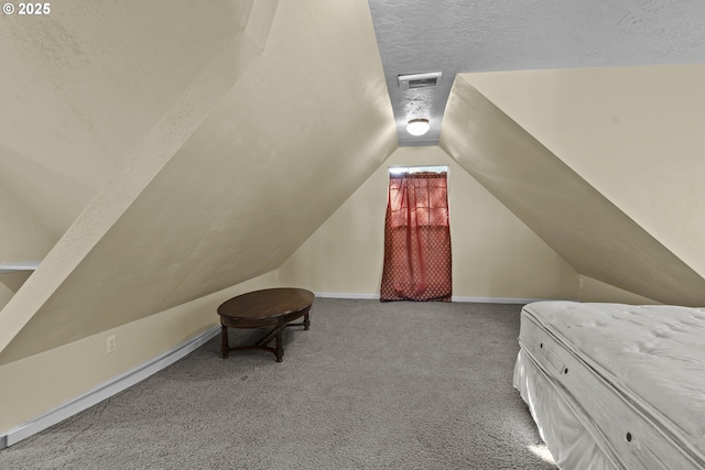 carpeted bedroom with vaulted ceiling, a textured ceiling, and baseboards