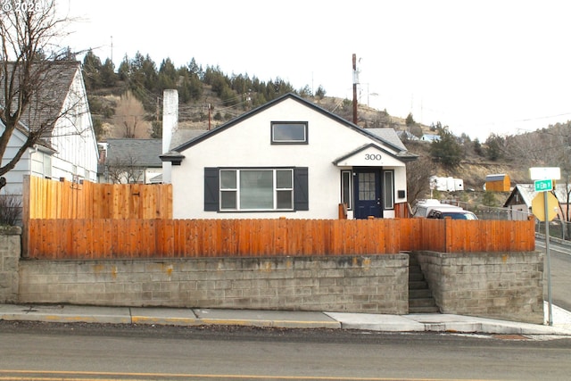 bungalow featuring a fenced front yard and stucco siding