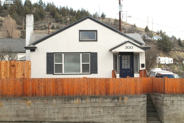 bungalow with a fenced front yard and stucco siding