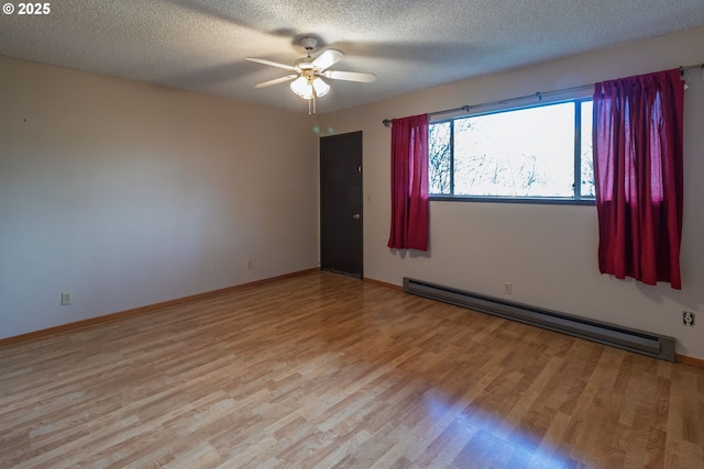 spare room featuring light wood-type flooring, a baseboard radiator, a textured ceiling, and a ceiling fan