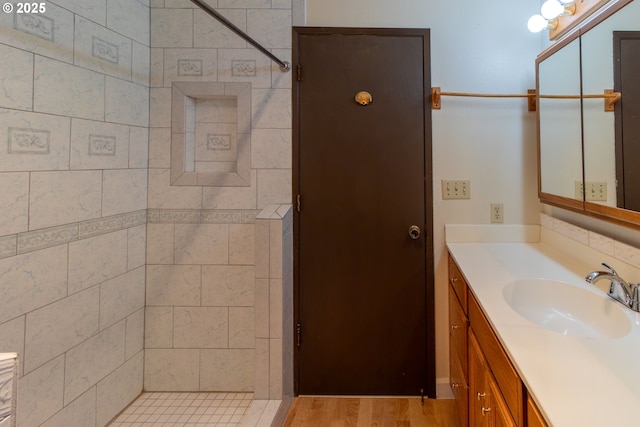 bathroom featuring tiled shower, vanity, and wood finished floors