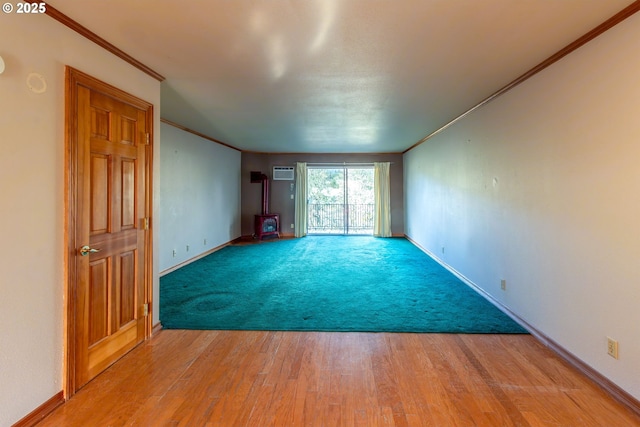 unfurnished room featuring light wood-style floors, a wood stove, a wall mounted air conditioner, and crown molding