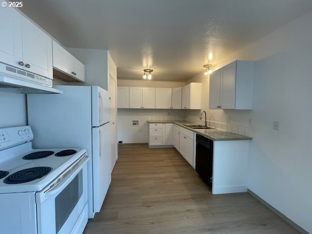 755735 Bluff Ave, Bandon, OR 97411 - kitchen with white electric range oven, a sink, black dishwasher, under cabinet range hood, and light wood-style floors