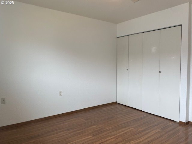 755735 Bluff Ave, Bandon, OR 97411 - unfurnished bedroom featuring dark wood-style floors, a closet, and baseboards