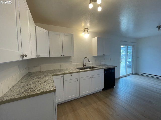 755735 Bluff Ave, Bandon, OR 97411 - kitchen with black dishwasher, a sink, light wood-style flooring, white cabinets, and baseboard heating