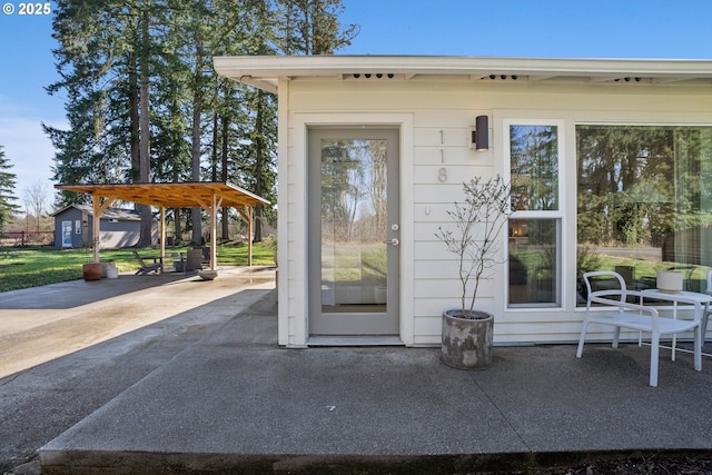 doorway to property featuring driveway, a carport, and a patio area