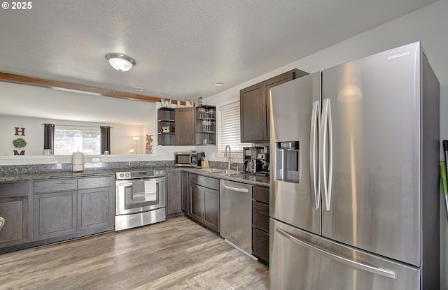 kitchen featuring sink, light hardwood / wood-style flooring, appliances with stainless steel finishes, dark brown cabinetry, and a textured ceiling