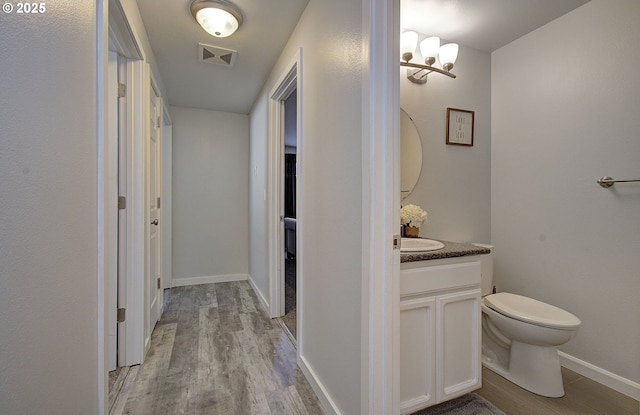 bathroom featuring wood-type flooring, vanity, and toilet