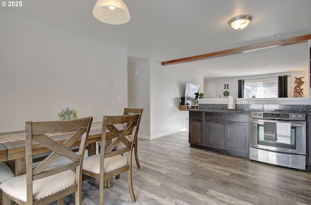 dining area with beam ceiling and light hardwood / wood-style floors