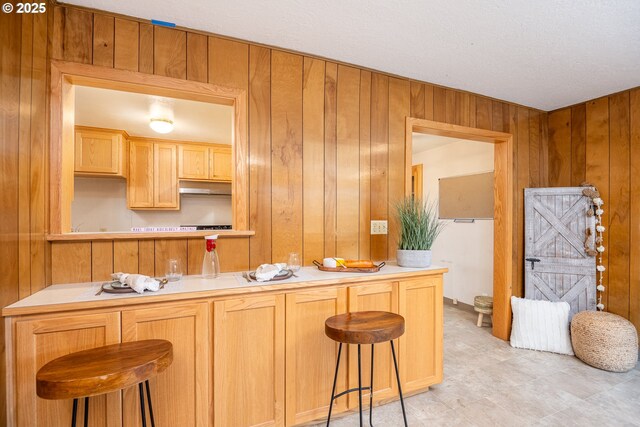 4160 Willhi St, Eugene, OR 97402 - kitchen featuring wooden walls, kitchen peninsula, a kitchen bar, and light brown cabinets