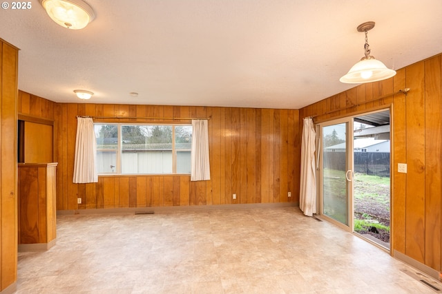 unfurnished living room with a healthy amount of sunlight and wooden walls