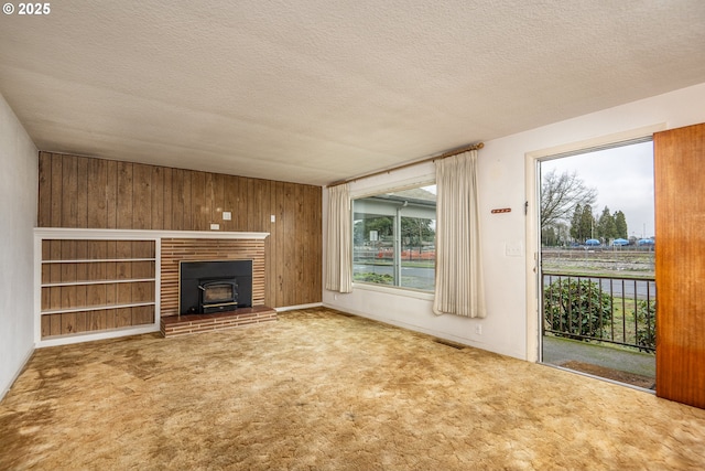 unfurnished living room featuring wooden walls, carpet, and a textured ceiling