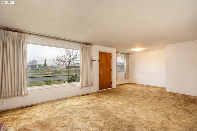 carpeted empty room featuring a water view and a textured ceiling