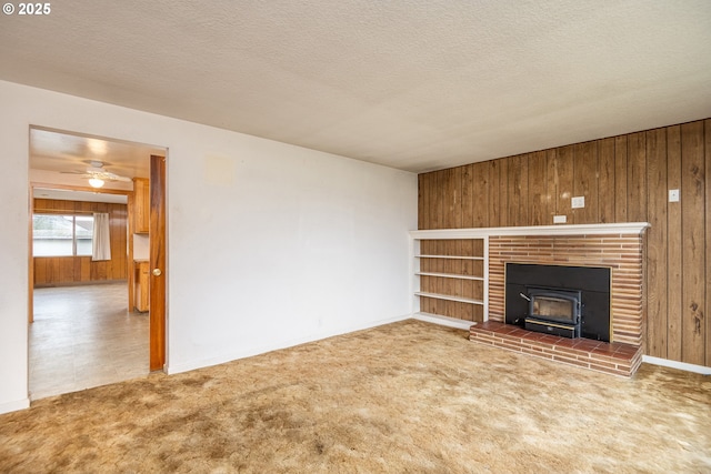 unfurnished living room featuring ceiling fan, carpet, a textured ceiling, and wood walls