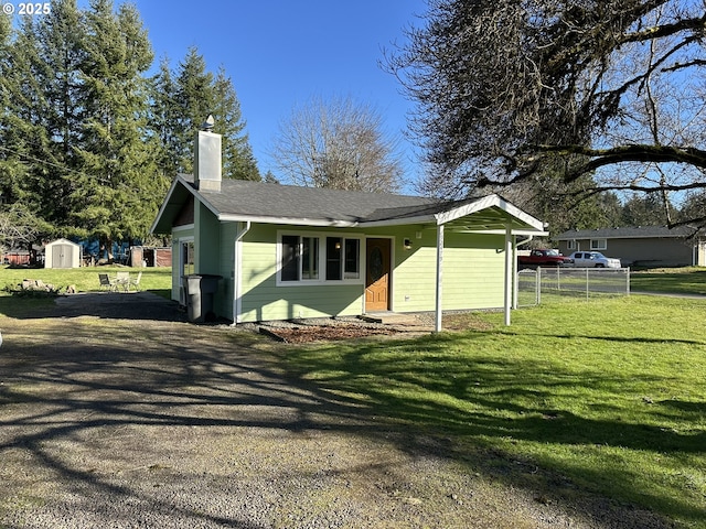 view of front facade with an outdoor structure, fence, a shed, a chimney, and a front yard