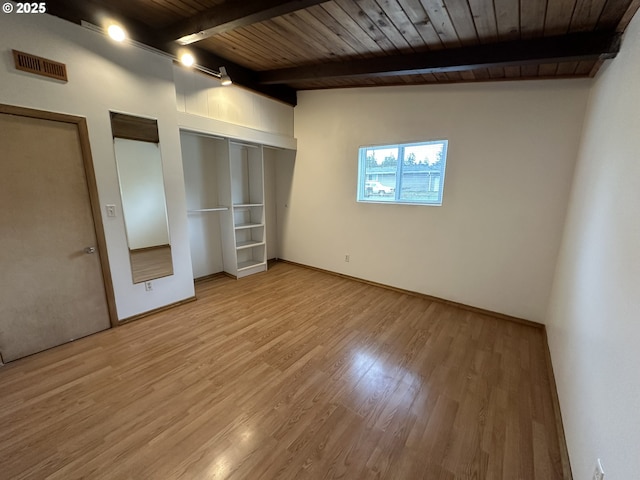 unfurnished bedroom with visible vents, lofted ceiling with beams, wood ceiling, wood finished floors, and two closets