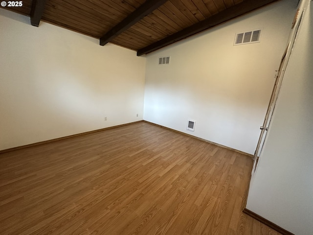 spare room with lofted ceiling with beams, visible vents, and wood finished floors