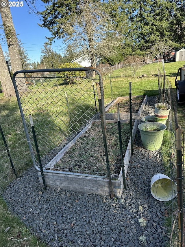 view of gate featuring a yard, a vegetable garden, and fence