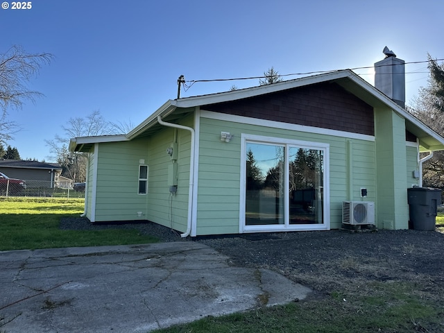 back of house featuring a lawn, a patio area, a chimney, fence, and ac unit