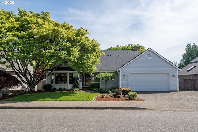 view of front facade with driveway, a chimney, an attached garage, fence, and a front lawn