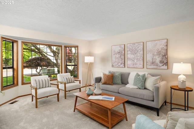 living room with a textured ceiling, visible vents, light colored carpet, and baseboards