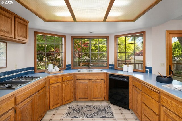 kitchen with a sink, brown cabinets, stovetop with downdraft, light countertops, and dishwasher