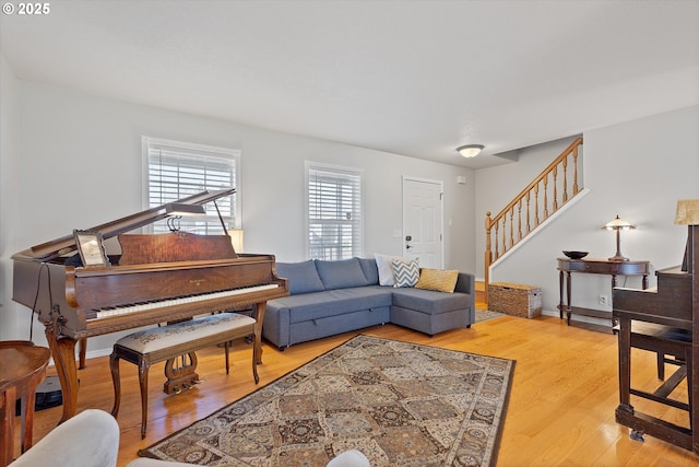 living area featuring baseboards, stairway, and wood finished floors