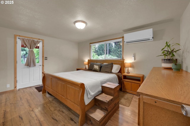 86680 Territorial Hwy, Veneta, OR 97487 - bedroom with a wall mounted air conditioner, light wood-style flooring, multiple windows, and a textured ceiling