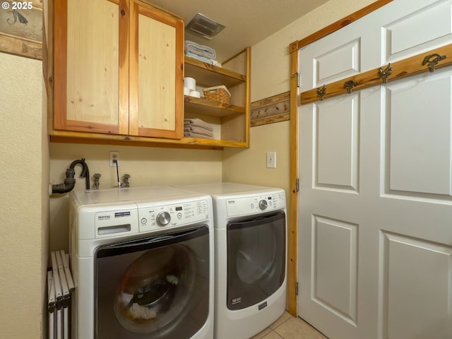 86680 Territorial Hwy, Veneta, OR 97487 - laundry area featuring cabinet space, washer and clothes dryer, and light tile patterned floors