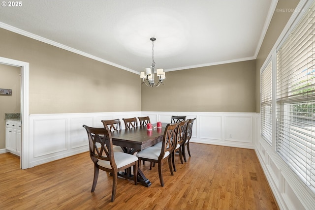 dining room featuring crown molding, visible vents, light wood-style flooring, and an inviting chandelier