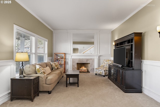 living room with crown molding, a fireplace, light colored carpet, and a decorative wall