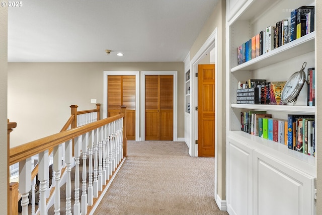 corridor featuring baseboards, light colored carpet, and an upstairs landing