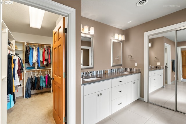 bathroom with a spacious closet, double vanity, a sink, and visible vents