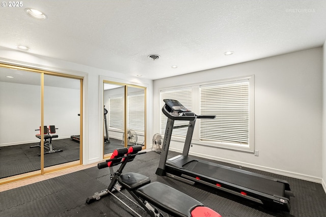 exercise area featuring baseboards, a textured ceiling, and recessed lighting