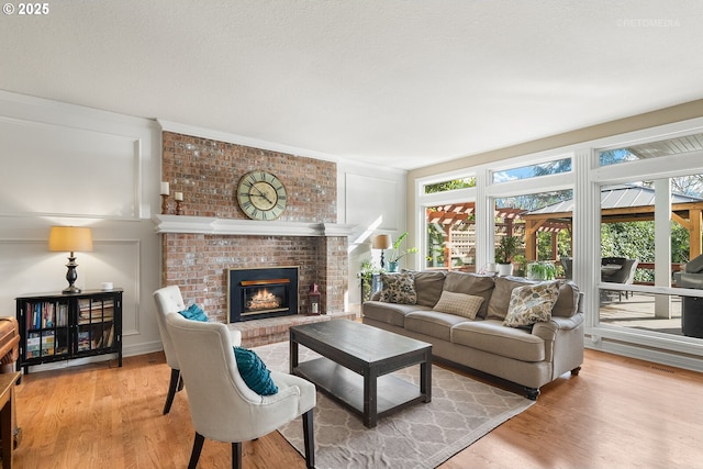 living room with a wealth of natural light, a fireplace, a decorative wall, and wood finished floors