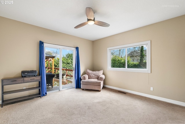 living area featuring a wealth of natural light, baseboards, and carpet