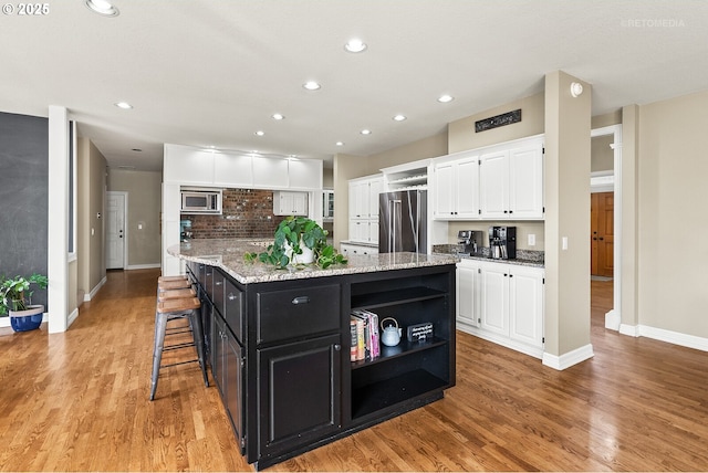 kitchen with a center island, stainless steel appliances, dark cabinetry, white cabinetry, and open shelves