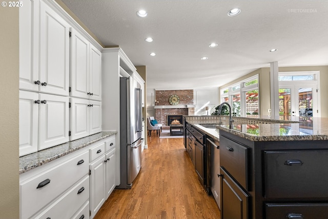 kitchen with a fireplace, a sink, white cabinetry, french doors, and freestanding refrigerator