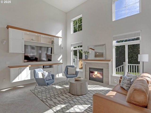 carpeted living area featuring high vaulted ceiling, a tile fireplace, and baseboards