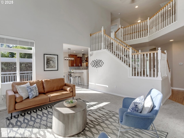 carpeted living room with a towering ceiling, stairway, baseboards, and recessed lighting