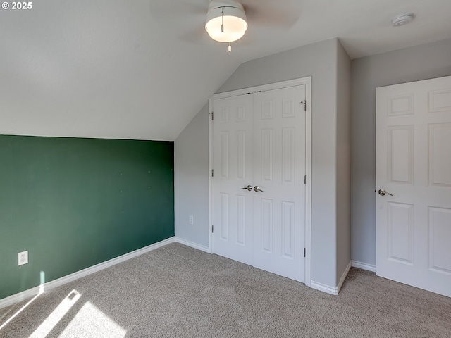 unfurnished bedroom featuring carpet, a closet, vaulted ceiling, a ceiling fan, and baseboards